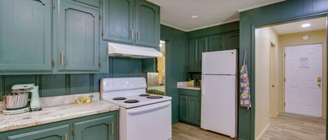 Una cocina con armarios verdes, estufa blanca y refrigerador.