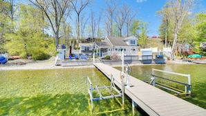 Une propriété au bord du lac, dotée d’un quai, d’une eau claire et d’une maison avec un patio couvert.