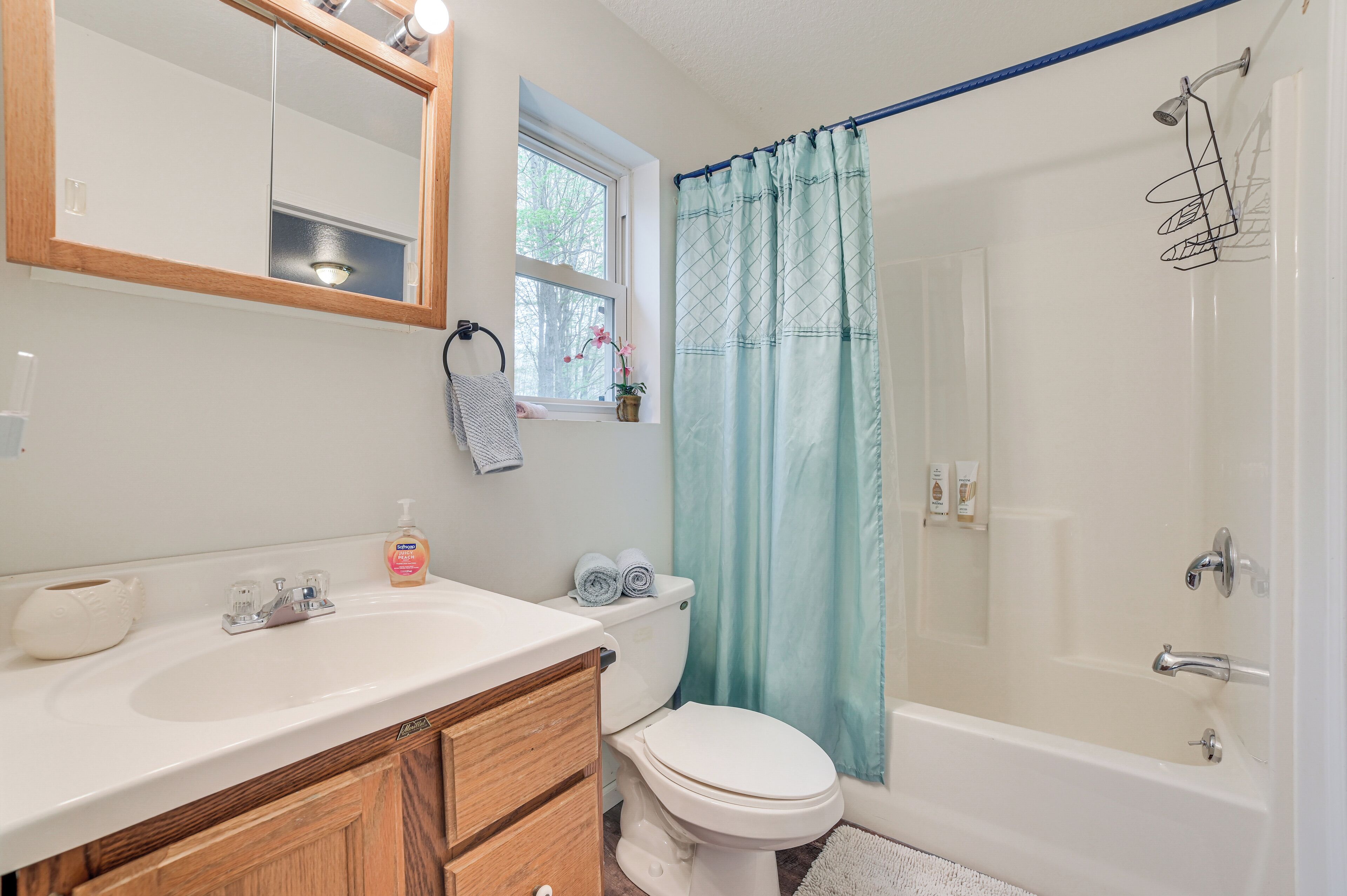 A bathroom with a white sink, wooden cabinets, a toilet, and a bathtub.