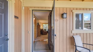 A wooden exterior with a sliding door leading to a living area with a sofa and a lamp.