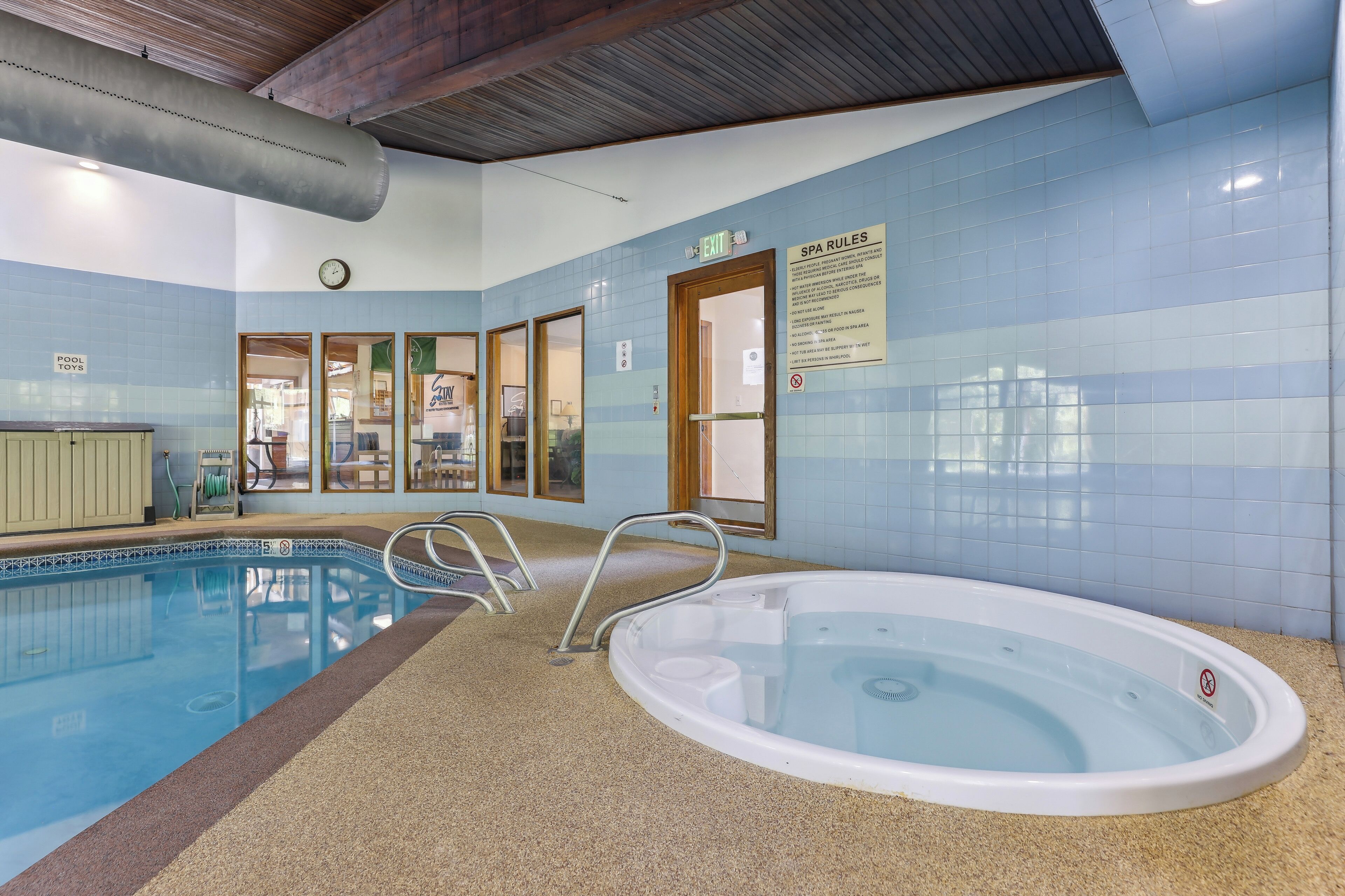 Un espace piscine comprenant un jacuzzi, des jeux de piscine et un panneau indiquant les règles du centre de bien-être.