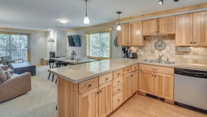 A modern kitchen with wooden cabinets, a built-in dishwasher, and a large island with a sink.