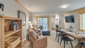 A cozy living room with a sofa, a dining table set for four, and a fireplace.