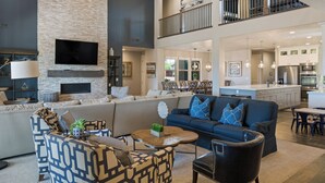 A spacious living area with a high ceiling, a fireplace, a large sofa, and a dining area with a kitchen in the background. - Great Escape #63: Private Hot Tub, Paradise Village Waterpark + Pools, Home Thea (Santa Clara)