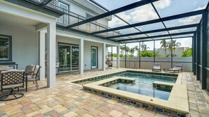 Une piscine extérieure couverte avec un espace patio comprenant des sièges et une table.