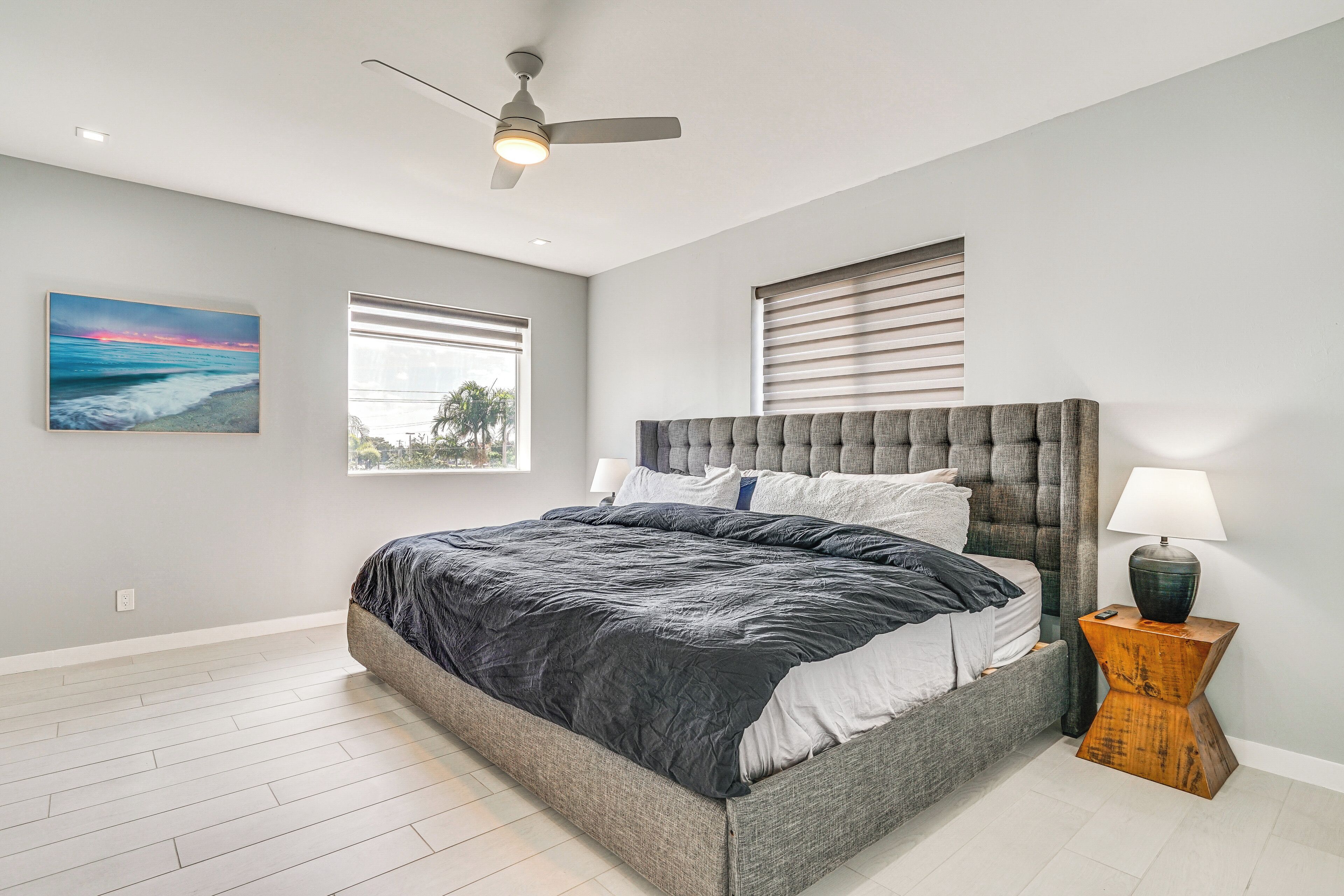 Une chambre à coucher avec un grand lit, un ventilateur de plafond et une table de chevet avec une lampe.