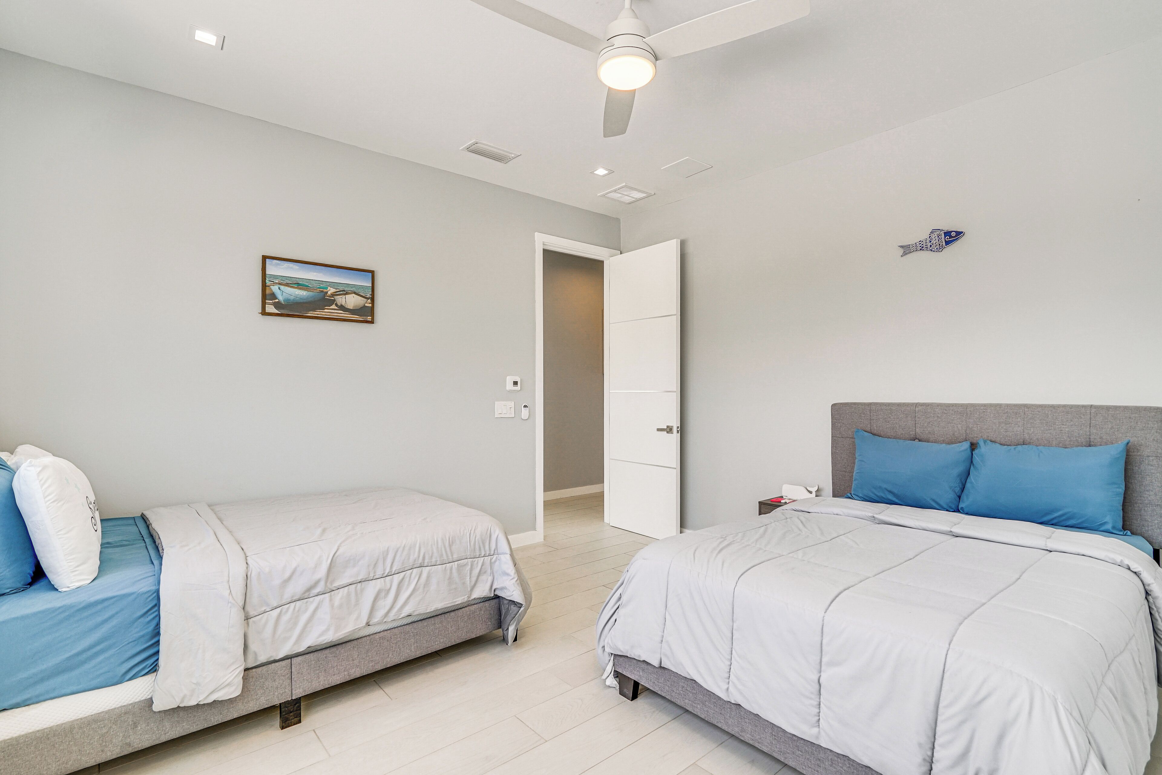 Un dormitorio con dos camas, un ventilador de techo y un cuadro en la pared.