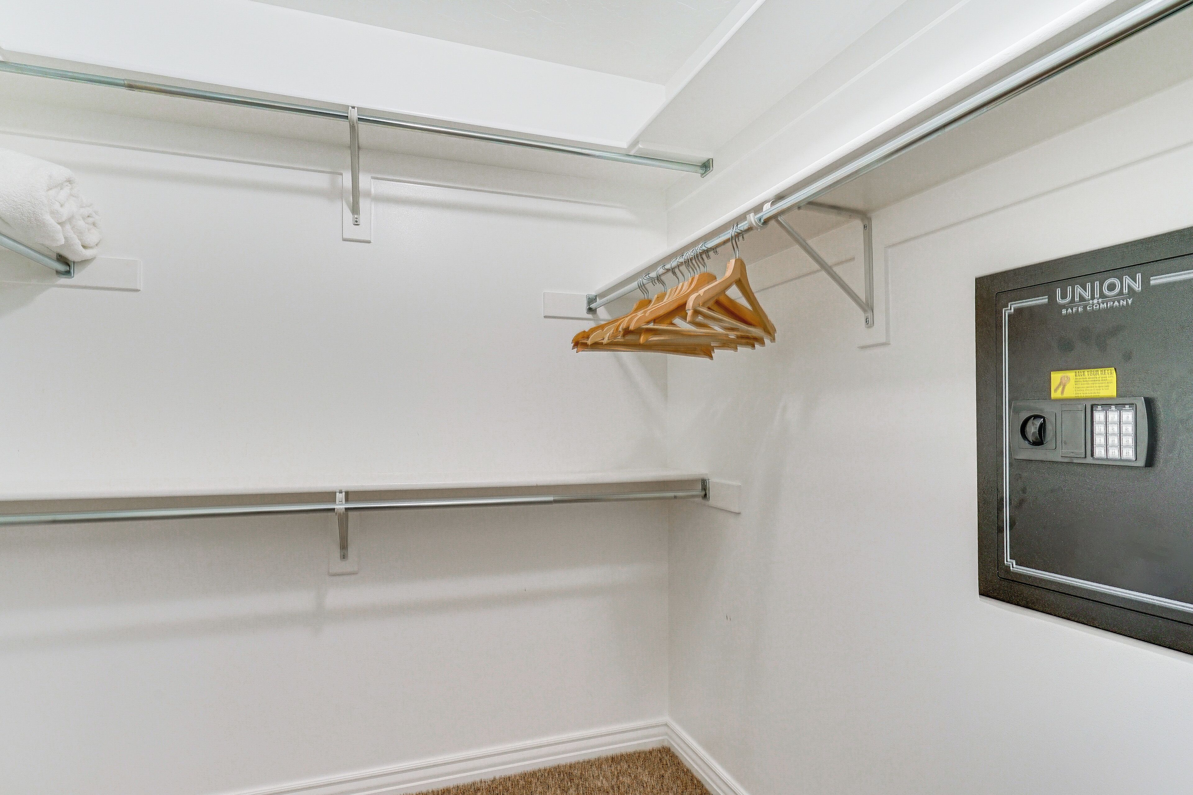 Un armario con barras metálicas para colgar ropa, un perchero y un panel de seguridad en la pared.