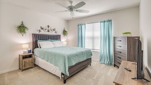 A bedroom with a bed, nightstand, dresser, TV, and ceiling fan. - Furnished Lanai & Golf Cart: the Villages Home! (Wildwood)