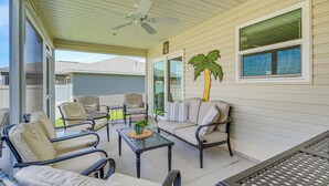 A covered patio with outdoor furniture, a ceiling fan, and a palm tree. - Furnished Lanai & Golf Cart: the Villages Home! (Wildwood)