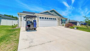 A single-story house with a garage, a driveway, and a lawn. - Furnished Lanai & Golf Cart: the Villages Home! (Wildwood)