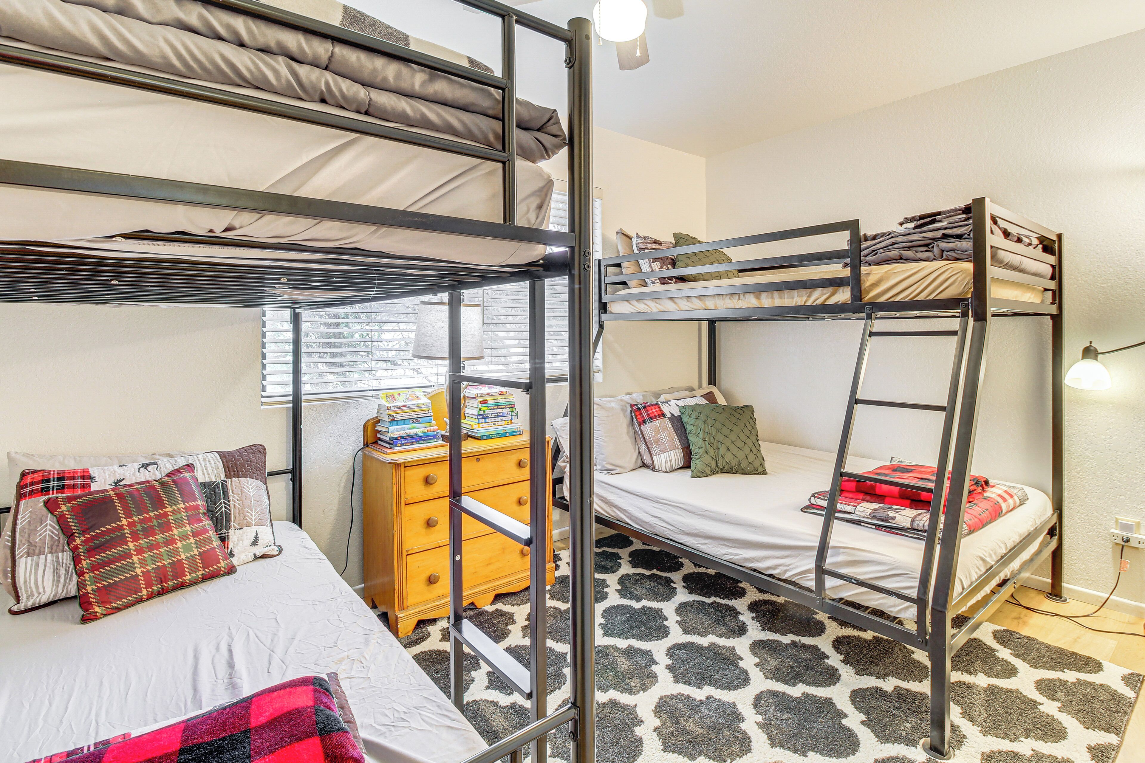 A dormitory room with bunk beds, a dresser, and a patterned rug.