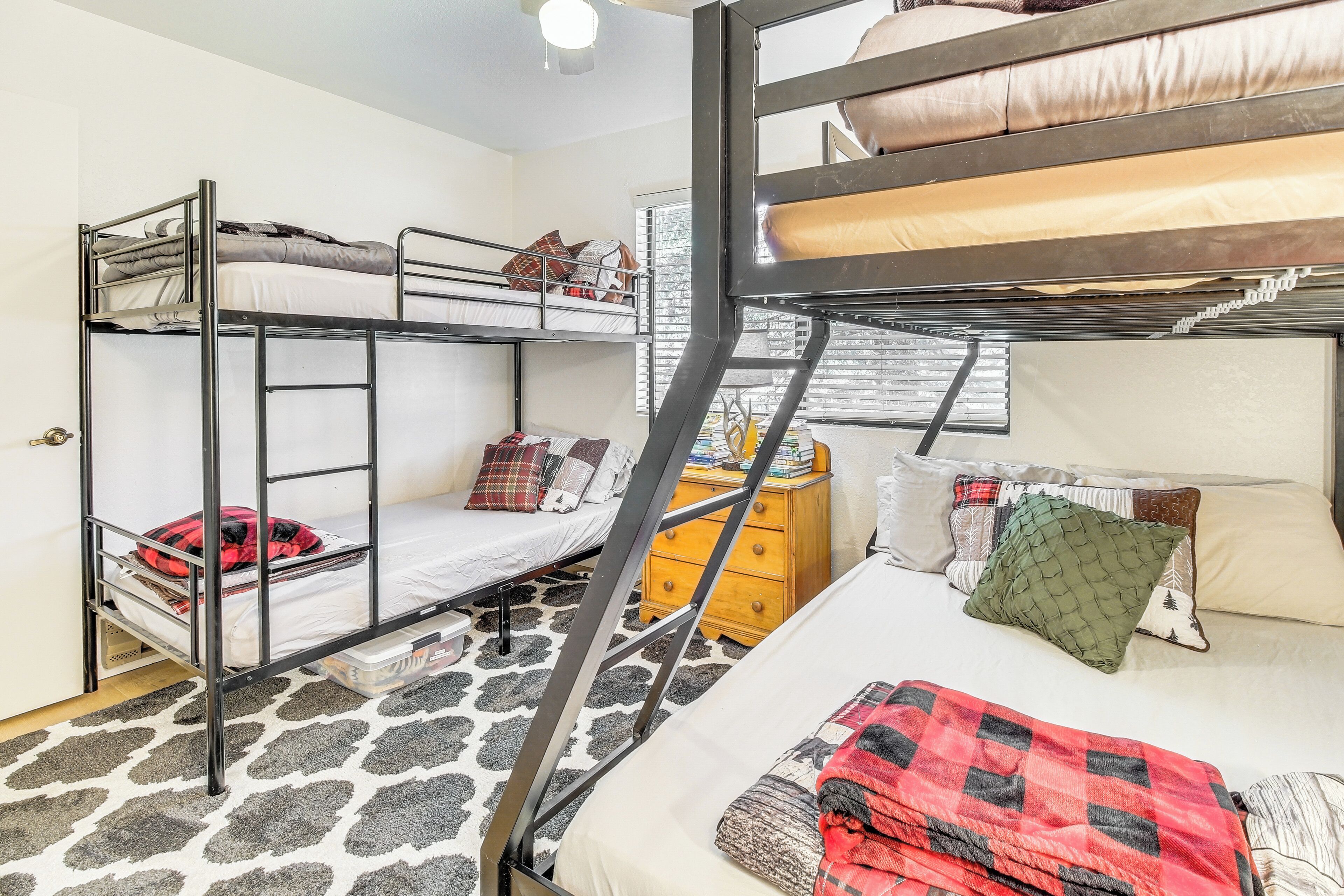 A dormitory room with bunk beds, a dresser, and a patterned carpet.