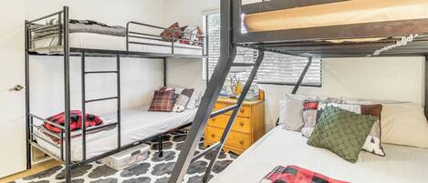 A dormitory room with bunk beds, a dresser, and a patterned carpet.