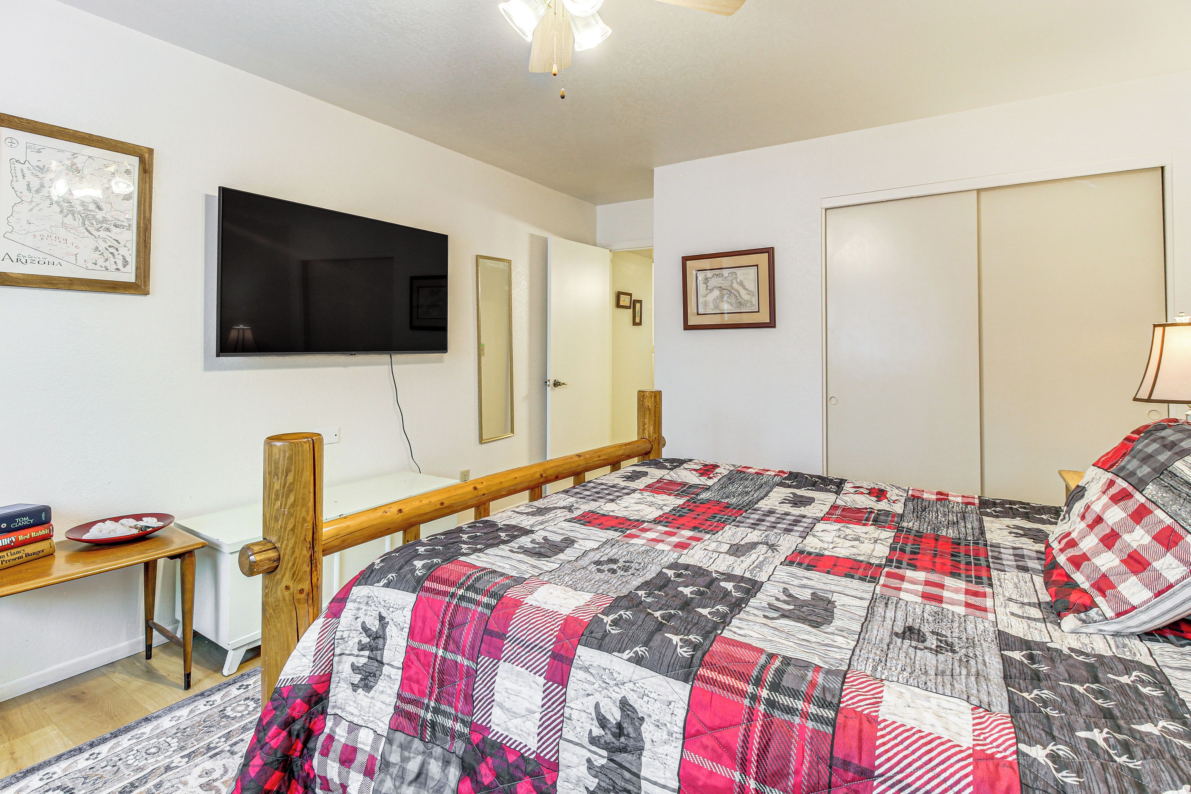 A bedroom with a bed, a TV mounted on the wall, a bedside table, and a wardrobe.