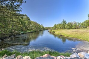 A calm river with a grassy bank and trees on both sides. - Lakefront Long Pond Home w/ Wraparound Deck! (Long Pond)