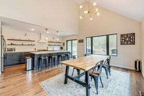 Een moderne keuken met een centraal eiland, barstoelen en een eettafel met stoelen.
