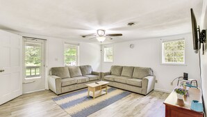 A living room with two sofas, a coffee table, a ceiling fan, and a window with a view of greenery. - Seneca Vacation Rental w/ Grill Near Lake Hartwell (Seneca)
