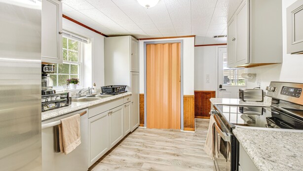 A modern kitchen with stainless steel appliances, a granite countertop, and wooden flooring. - Seneca Vacation Rental w/ Grill Near Lake Hartwell (Seneca)