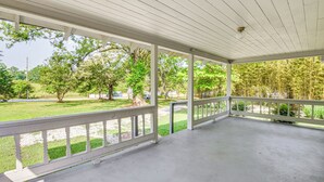 A covered porch with white railings, a concrete floor, and a view of a grassy area with trees. - Seneca Vacation Rental w/ Grill Near Lake Hartwell (Seneca)