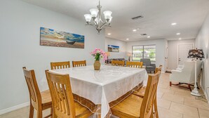A dining area with a round table, wooden chairs, a chandelier, and artwork on the walls. - 5 Mi to Weeki Wachee! Home w/ Lanai & Air Hockey (Spring Hill)