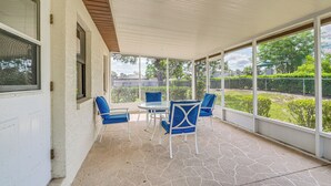 A covered patio with a table and four chairs, large windows, and a view of greenery. - 5 Mi to Weeki Wachee! Home w/ Lanai & Air Hockey (Spring Hill)