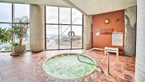 A spa area with a hot tub, large windows, and a wooden wall with a clock.