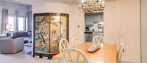 A dining area with a wooden table, white chairs, and a decorative screen.