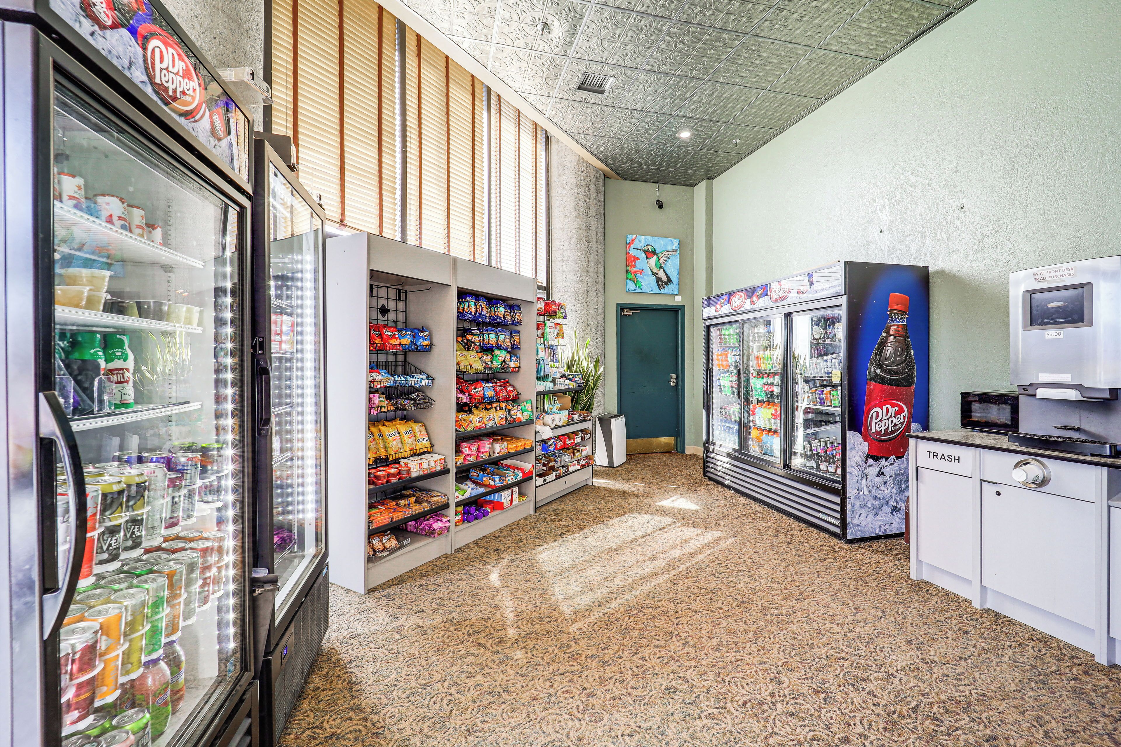 A vending area with various snack and drink options, including Dr. Pepper and other brands, and a trash bin.