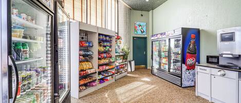 A vending area with various snack and drink options, including Dr. Pepper and other brands, and a trash bin.