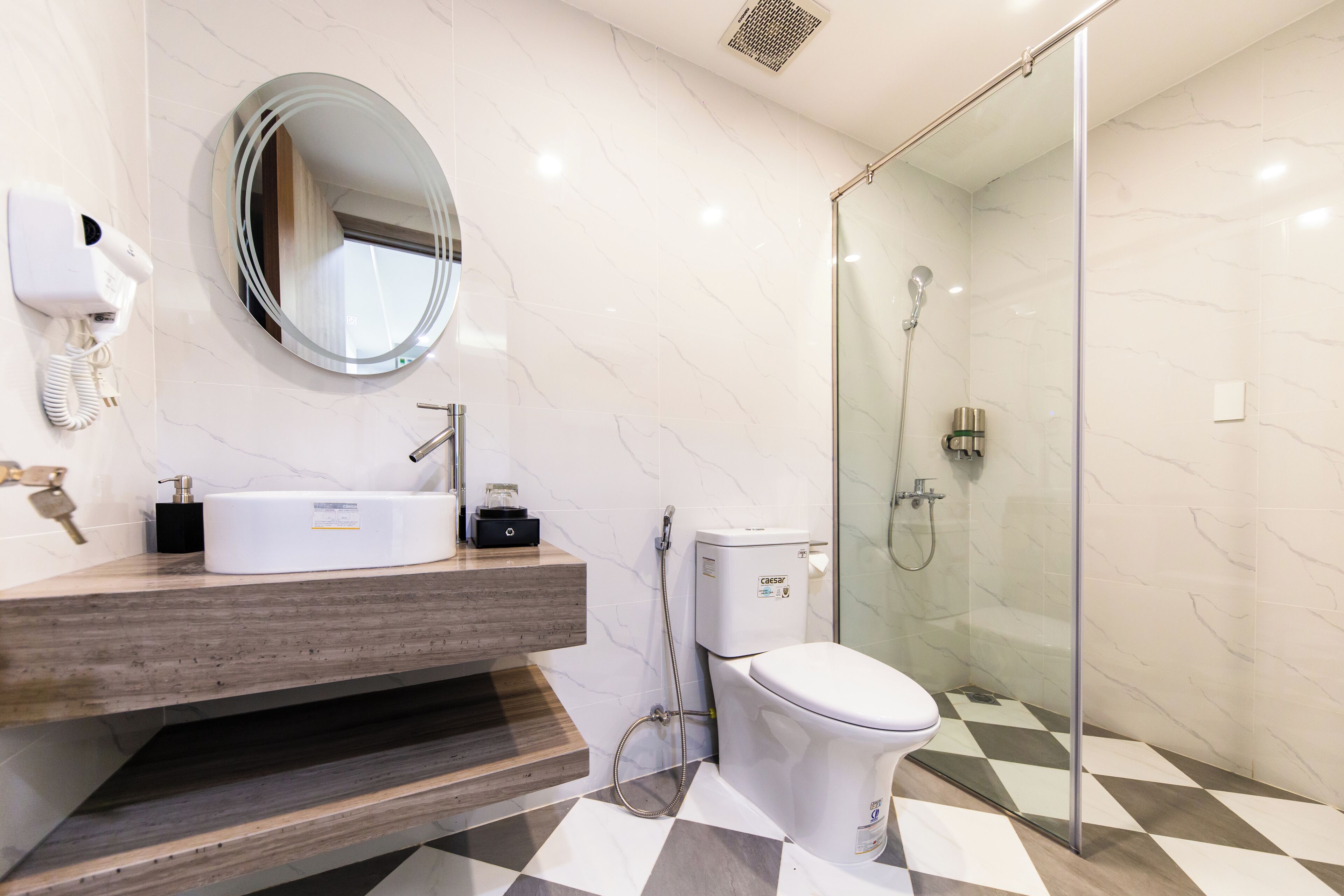 A modern bathroom with a marble vanity, a toilet, and a glass-enclosed shower.