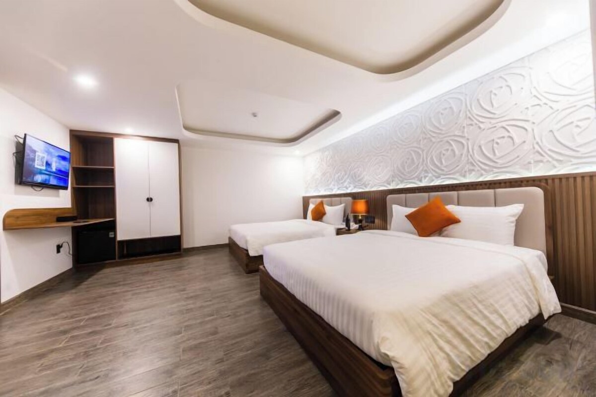 A hotel room with a large bed, a TV, a wardrobe, and a decorative ceiling.
