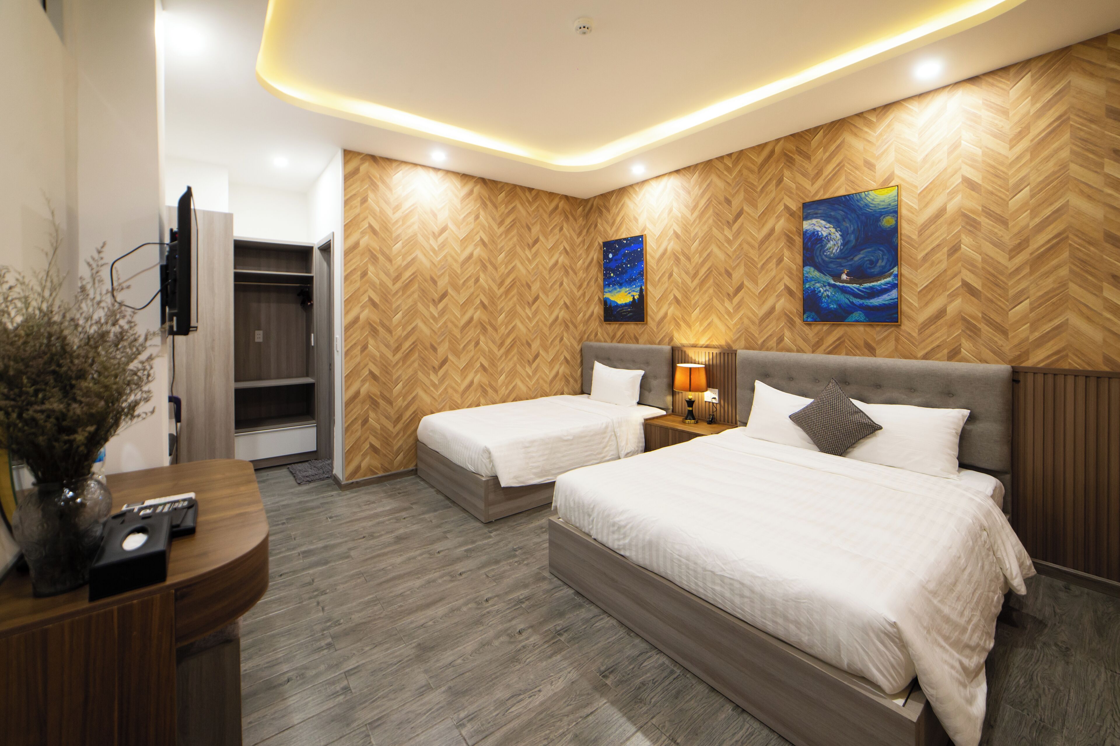 Una habitación de hotel moderna con dos camas, un patrón de pared de madera tipo espiga y un cuadro de un cielo nocturno.