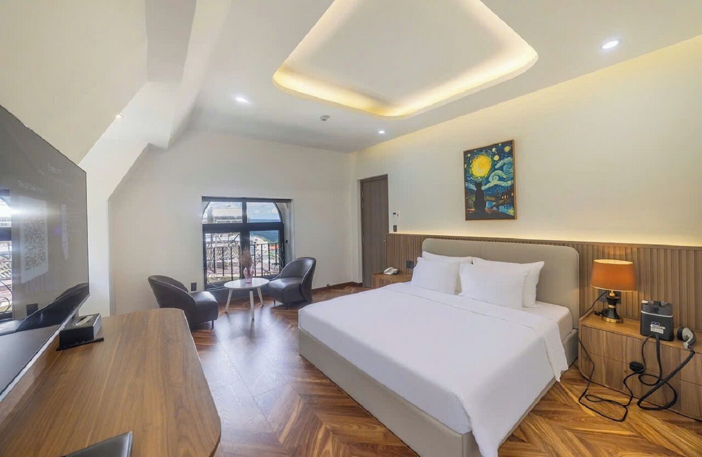 Une chambre d’hôtel avec un lit, un bureau, une chaise, une lampe et un tableau au mur.