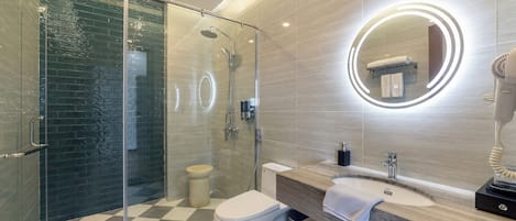 Une salle de bain moderne avec une douche à parois de verre, des toilettes et un meuble-lavabo avec un miroir.
