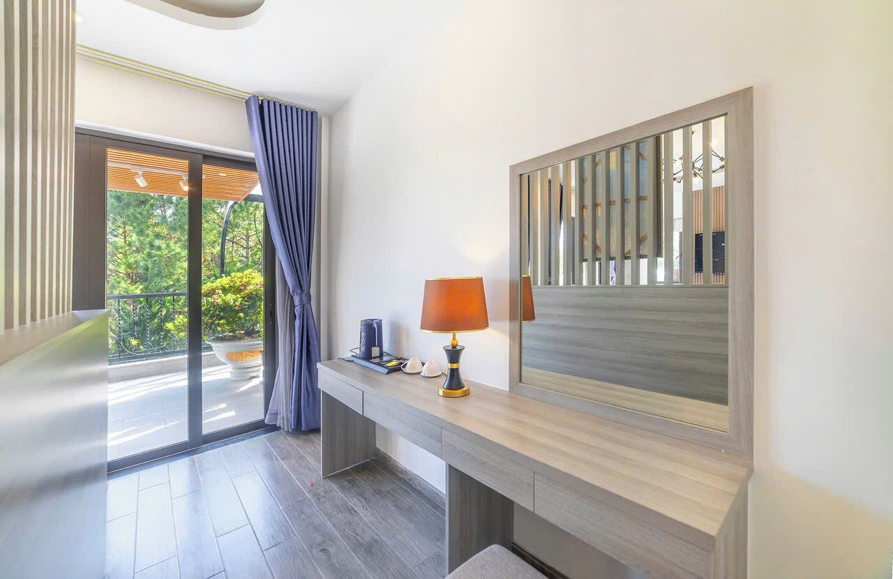 A modern bathroom with a large mirror, a wooden vanity, and a view of greenery outside.
