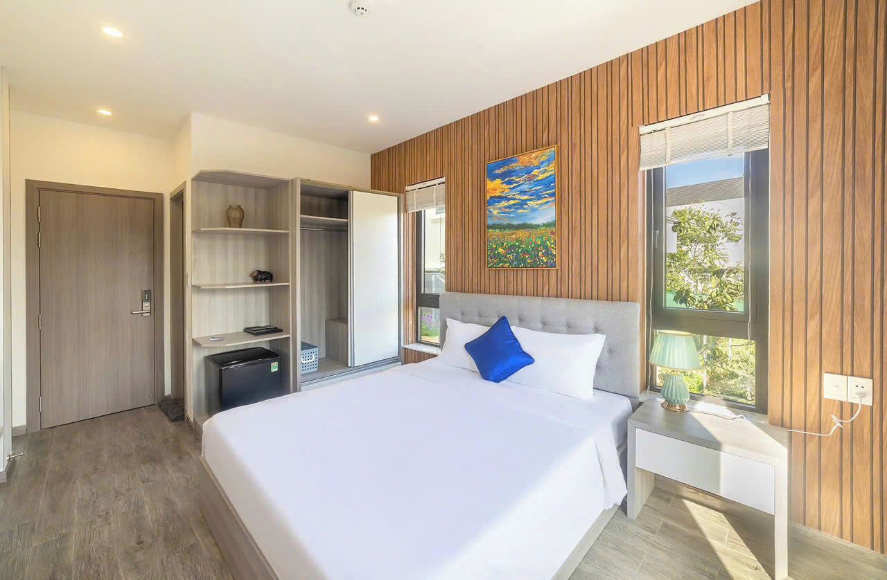 A modern bedroom with a large bed, a wardrobe, a built-in desk, and a window with a view.