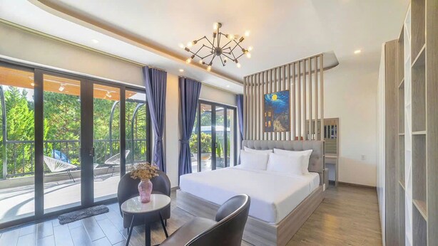 A modern hotel room with a large bed, a dining table, and a view of the outdoors. - TP Dalat Hotel (Xuan Huong - Da Lat)
