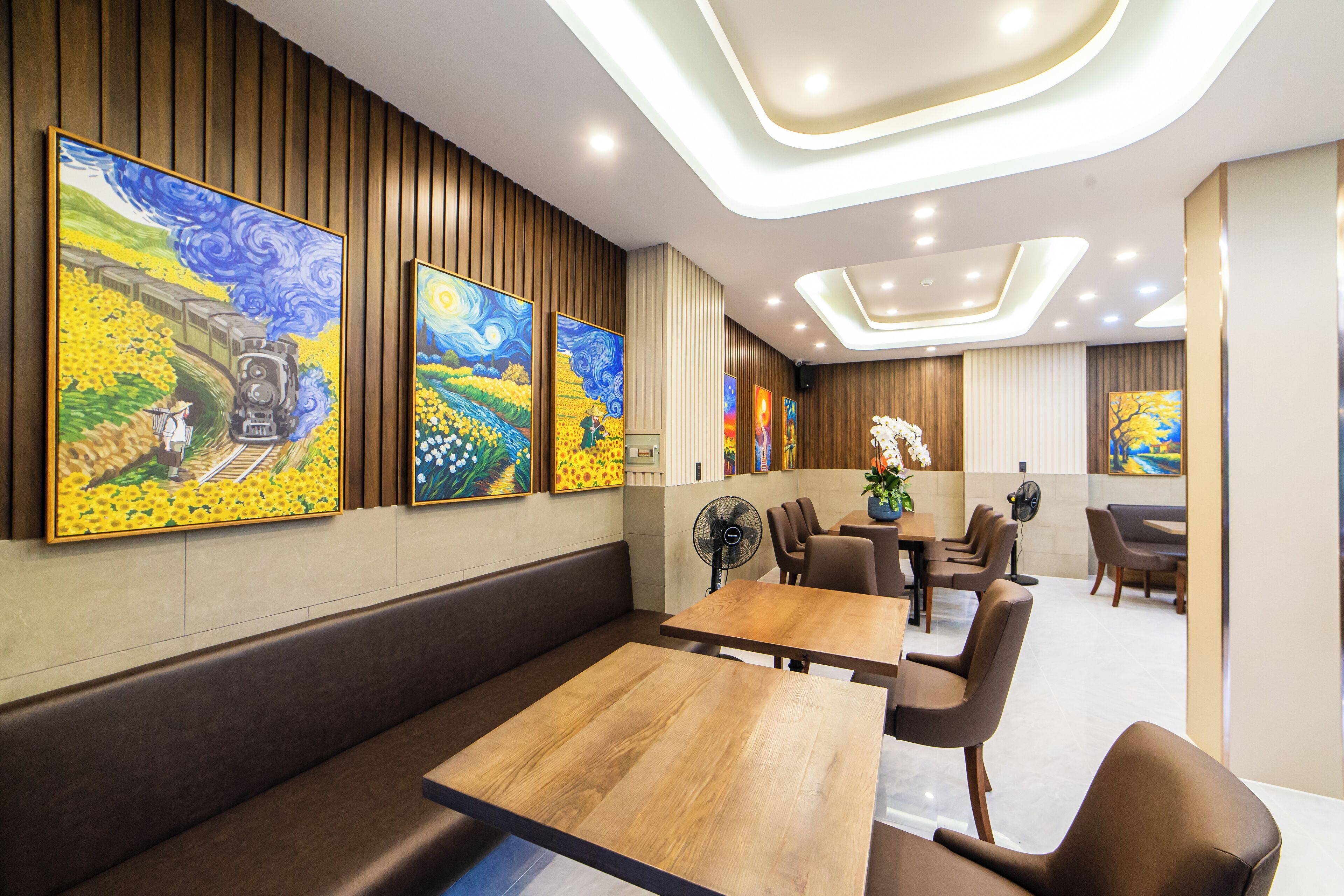 Un restaurant aux murs lambrissés, orné de tableaux et doté d’un éclairage moderne.