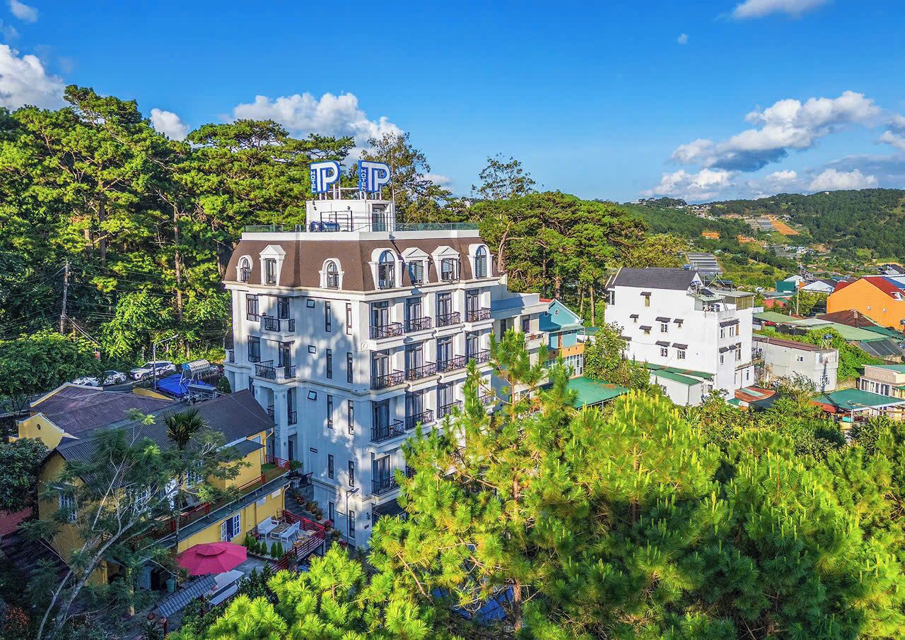 A multi-story building with balconies, surrounded by greenery and other buildings.