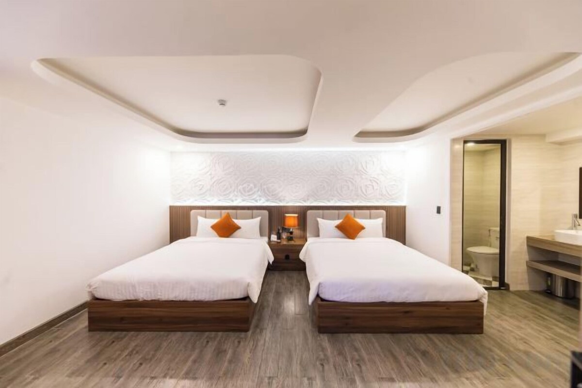 Habitación de hotel con dos camas, baño y diseño moderno.