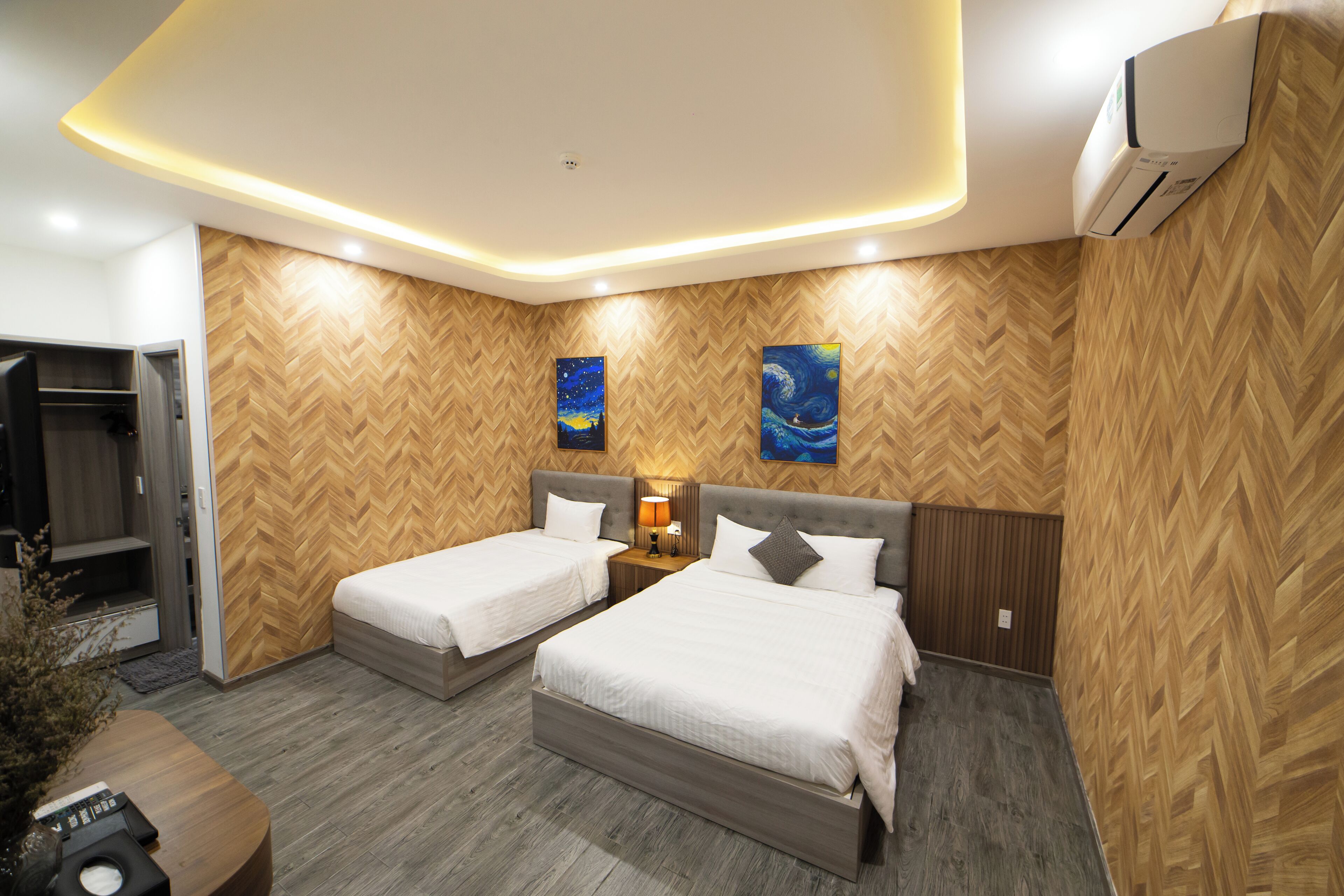 Une chambre d’hôtel avec deux lits, un mur en bois décoré d’un motif en chevrons, une peinture représentant un ciel étoilé et un design moderne au plafond.