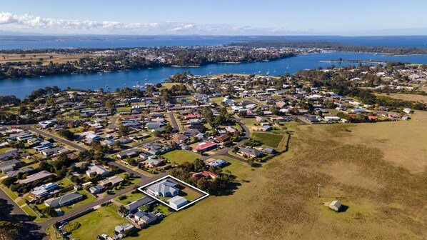Vista aérea de una zona residencial con casas, caminos y una gran masa de agua al fondo.