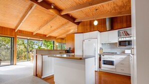 A modern kitchen with a central island, white cabinetry, and a view of the outdoors. - Anchorage Views: Indulge in the ultimate coastal getaway at Anchorage Views (Metung)
