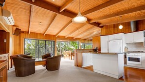 A spacious kitchen with white cabinets, a central island, and a dining area with wicker chairs. - Anchorage Views: Indulge in the ultimate coastal getaway at Anchorage Views (Metung)