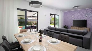 A modern living room with a dining area, a sofa, and a TV. - Villa Rudina, a luxurious villa near the beach (Pomer)
