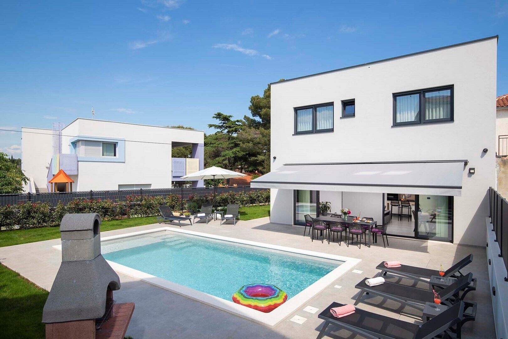 Een modern herenhuis met een zwembad, terras en een barbecuehoek.