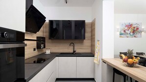 A modern kitchen with a black stove, white cabinets, a black countertop, and a wooden backsplash. - Villa Rudina, a luxurious villa near the beach (Pomer)