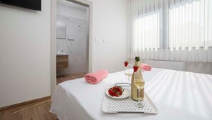 A hotel room with a bed, a tray with a bottle and glasses, a pink towel, and a plate with strawberries. - Villa Rudina, a luxurious villa near the beach (Pomer)