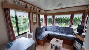 A cozy room with a sofa, a small table, a TV, and a window with curtains. - Tour de France Retreat (Gouvets)
